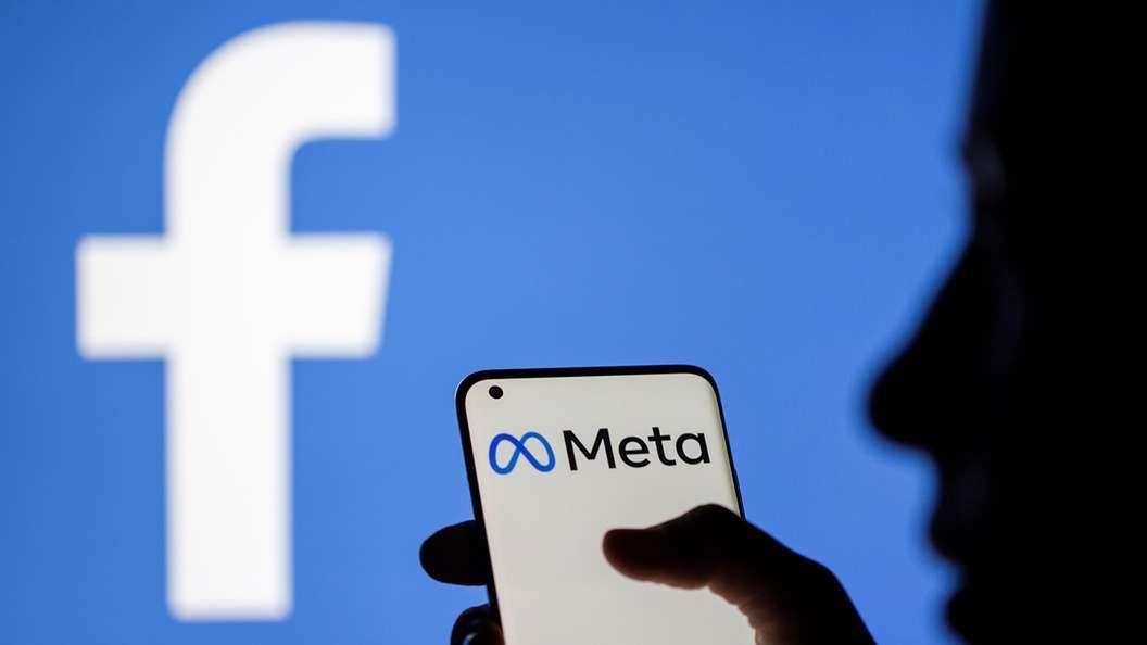 A woman holds a smartphone with Meta logo on it in front of a displayed Facebook logo in this illustration taken, October 28, 2021. REUTERS/Dado Ruvic/Illustration